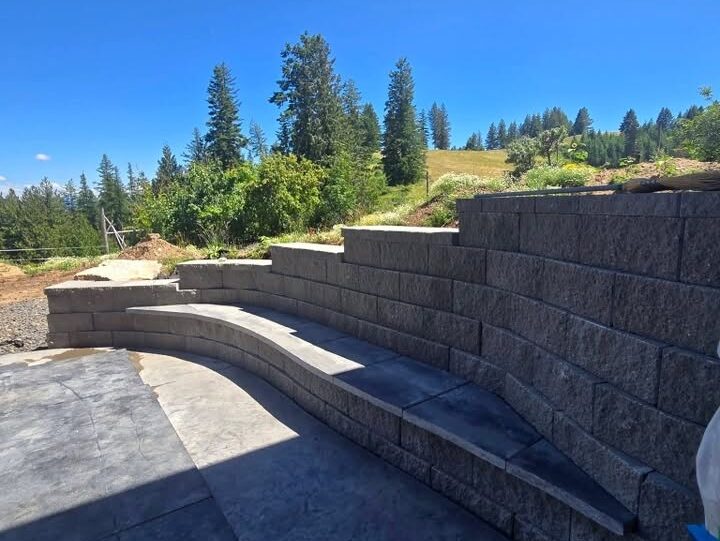 Curved Block Retaining Wall with Built-In Bench and Stamped Concrete Patio Curved segmental block retaining wall with built-in bench seating and stamped concrete patio, built by Jeske Construction in North Central Idaho